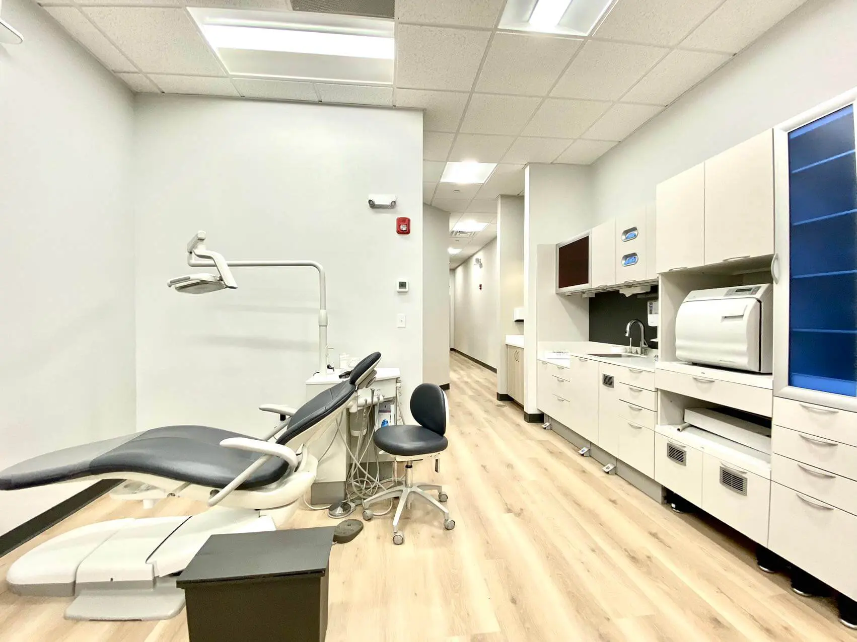 The dental exam room at Sweet Smiles Orthodontics in Arlington MA, features a modern chair, bright lighting, and wood floors.