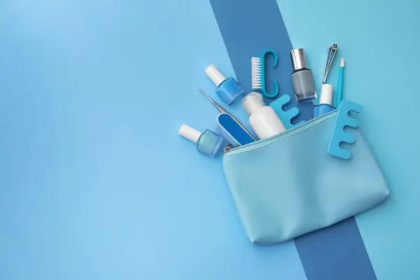 A small blue pouch with nail care tools and polishes, on a blue background—travel essentials from Sweet Smiles Orthodontics in Arlington, MA.