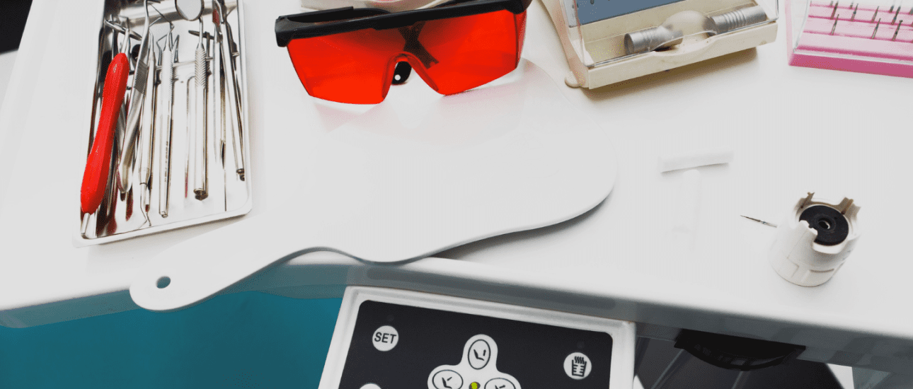 At Sweet Smiles Orthodontics in Arlington, MA: a dental tray with instruments, metal braces, red safety glasses, mirror, and control panel.