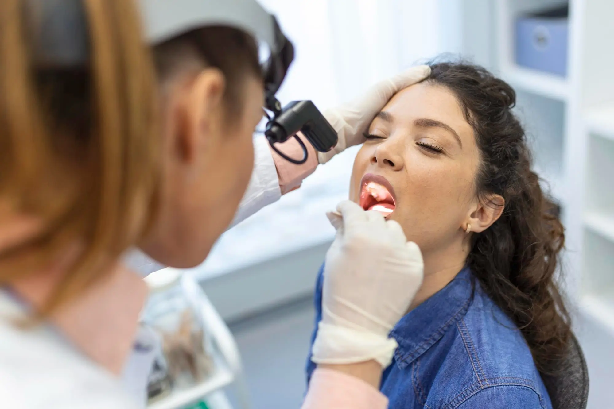 Dental professional examines patient's tongue position and oral function during tongue thrust evaluation, using specialized diagnostic tools to assess swallowing patterns and tongue placement at Sweet Smiles Orthodontics in Arlington, MA