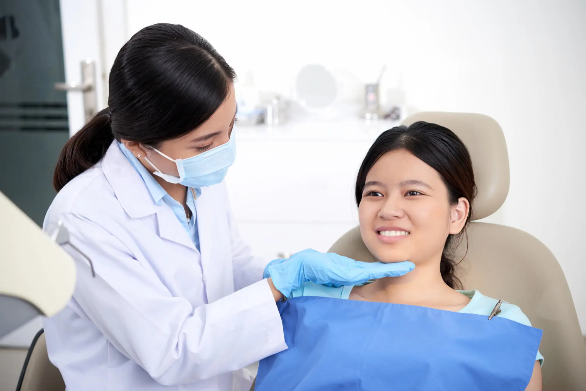 A dentist checks a woman's teeth at Sweet Smiles Orthodontics in Arlington, MA, highlighting jaw surgery consultation