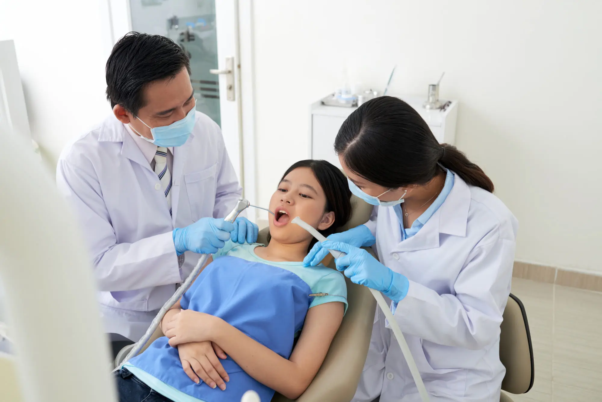 At Sweet Smiles Orthodontics in Arlington, MA, two masked dentists examine a young patient’s teeth with
orthodontic appliances.
