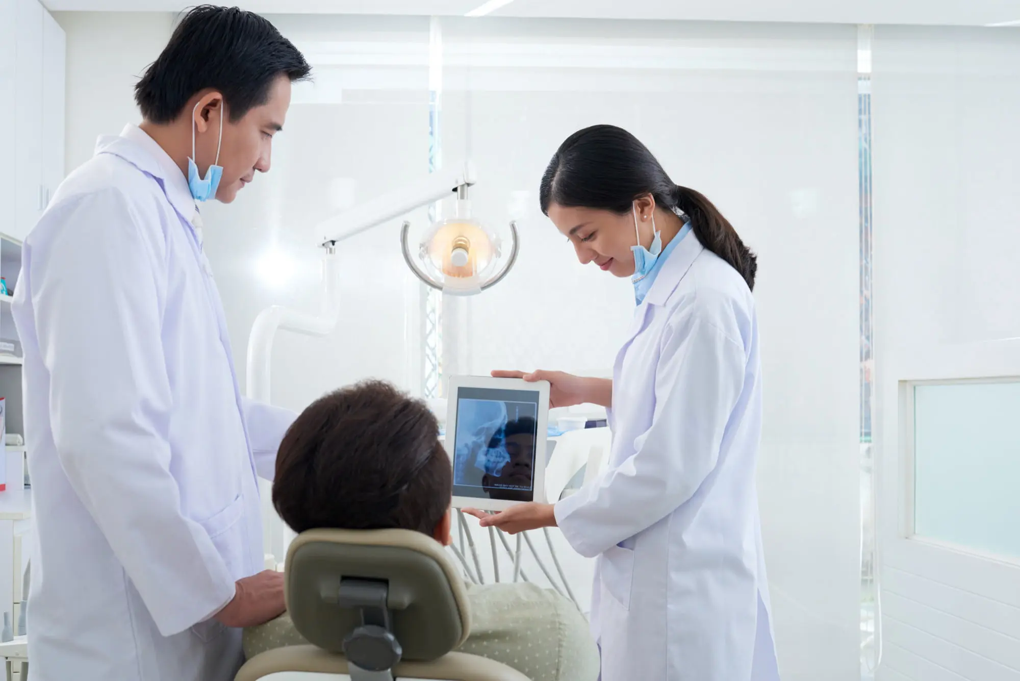 A man and woman in a dental office look at a tablet, exploring jaw surgery options at Sweet Smiles Orthodontics, Arlington, MA