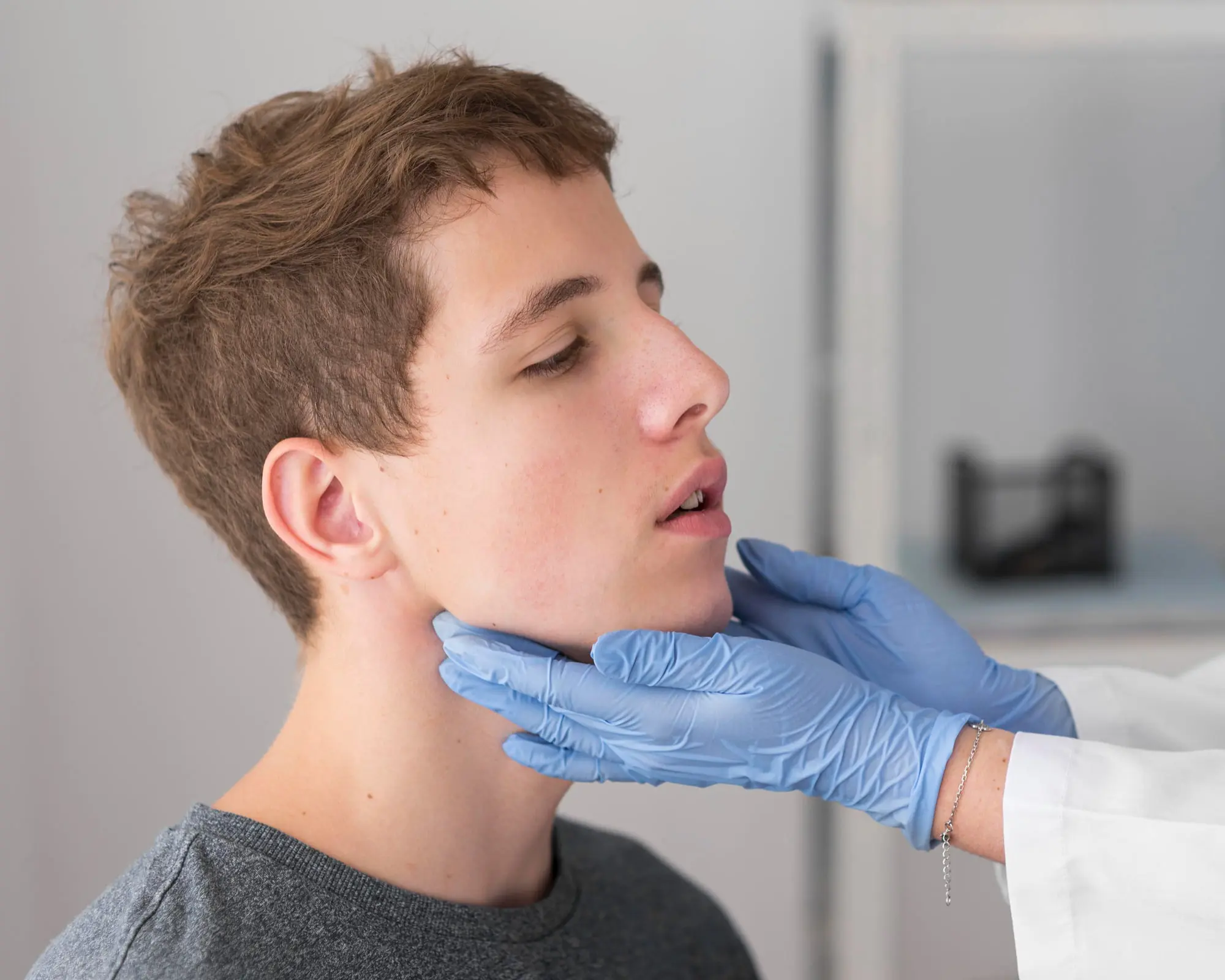 doctor checks a young man's neck as part of a jaw surgery consultation at Sweet Smiles Orthodontics in Arlington, MA