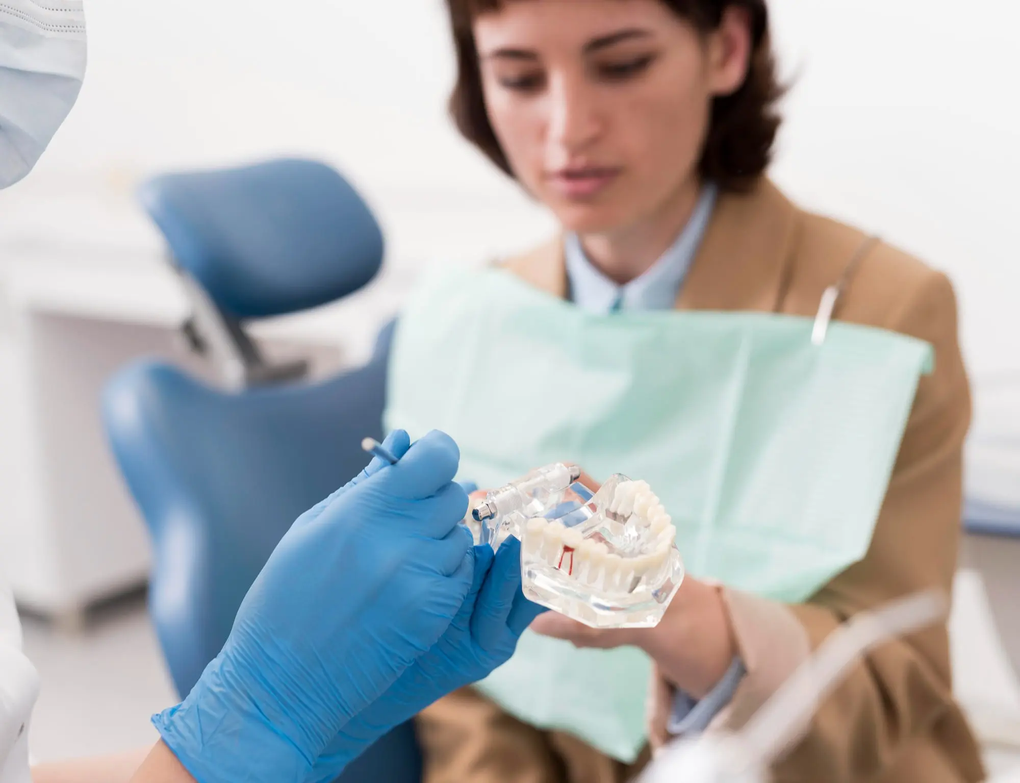 A dentist examines a tooth held by a woman during a jaw surgery consultation at Sweet Smiles Orthodontics in Arlington, MA