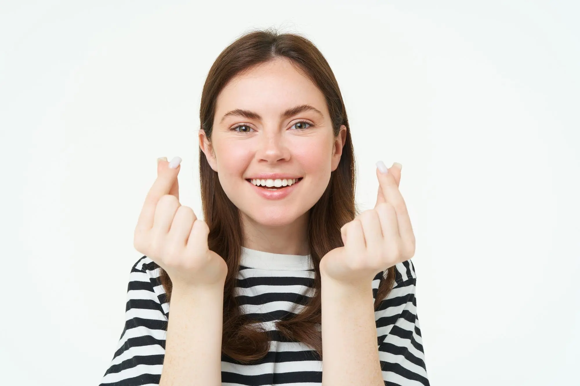 Smiling woman in a striped shirt makes finger-hearts, representing trusted Invisalign clear aligners at Sweet Smiles Orthodontics in Arlington, MA, on white background.