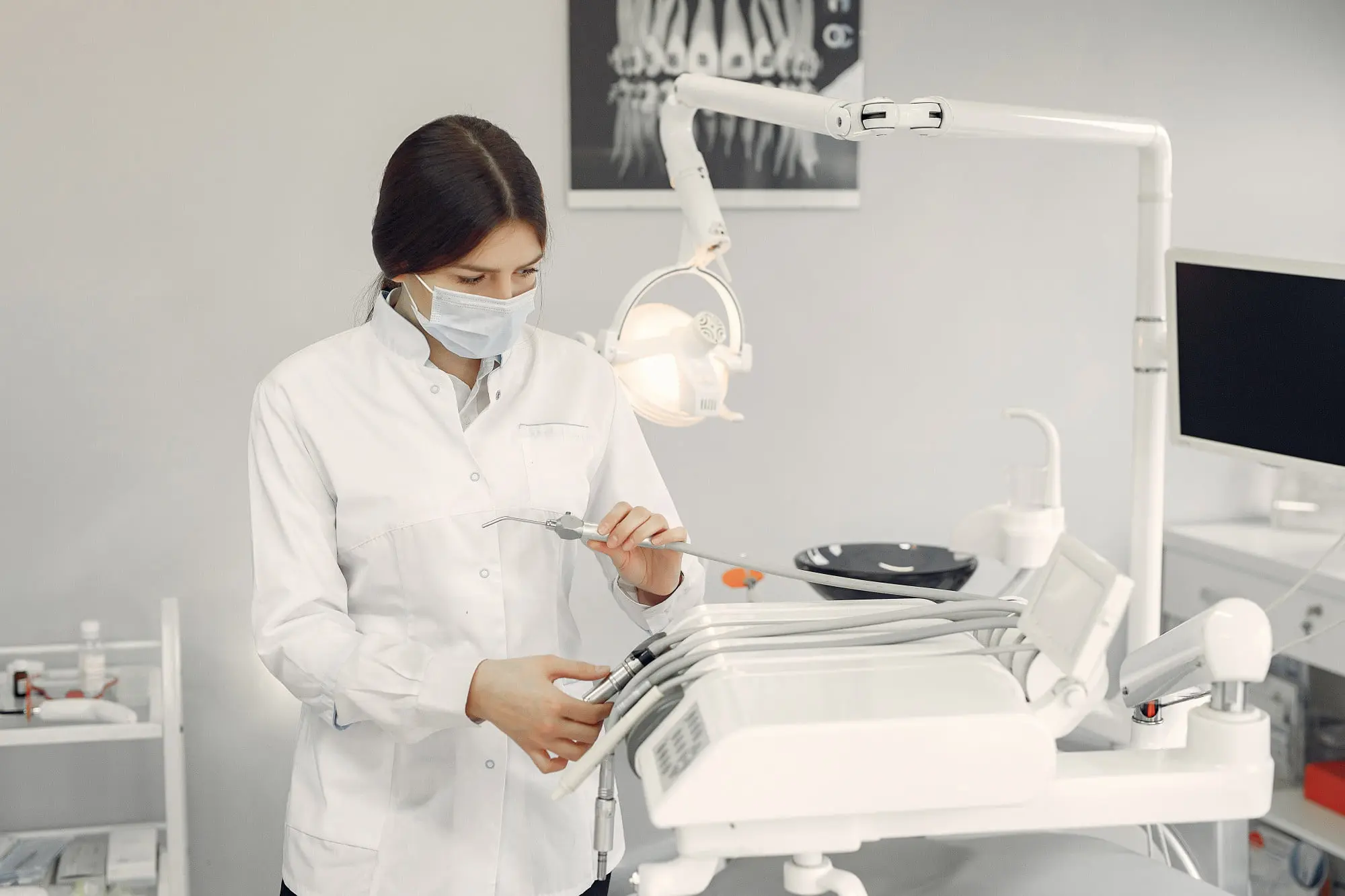 At Sweet Smiles Orthodontics in Arlington, MA, a masked dentist prepares instruments amid equipment and orthodontic insurance plans.