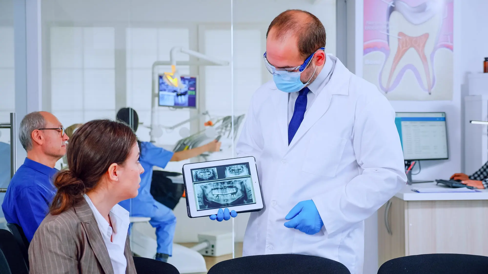 A man in a lab coat is using a tablet to discuss jaw surgery at Sweet Smiles Orthodontics in Arlington, MA