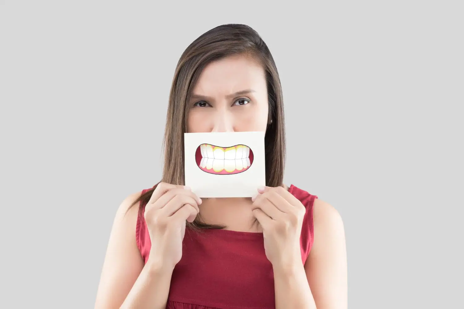 At Sweet Smiles Orthodontics, a woman displays a paper featuring a tooth, highlighting underbite concerns in Arlington, MA