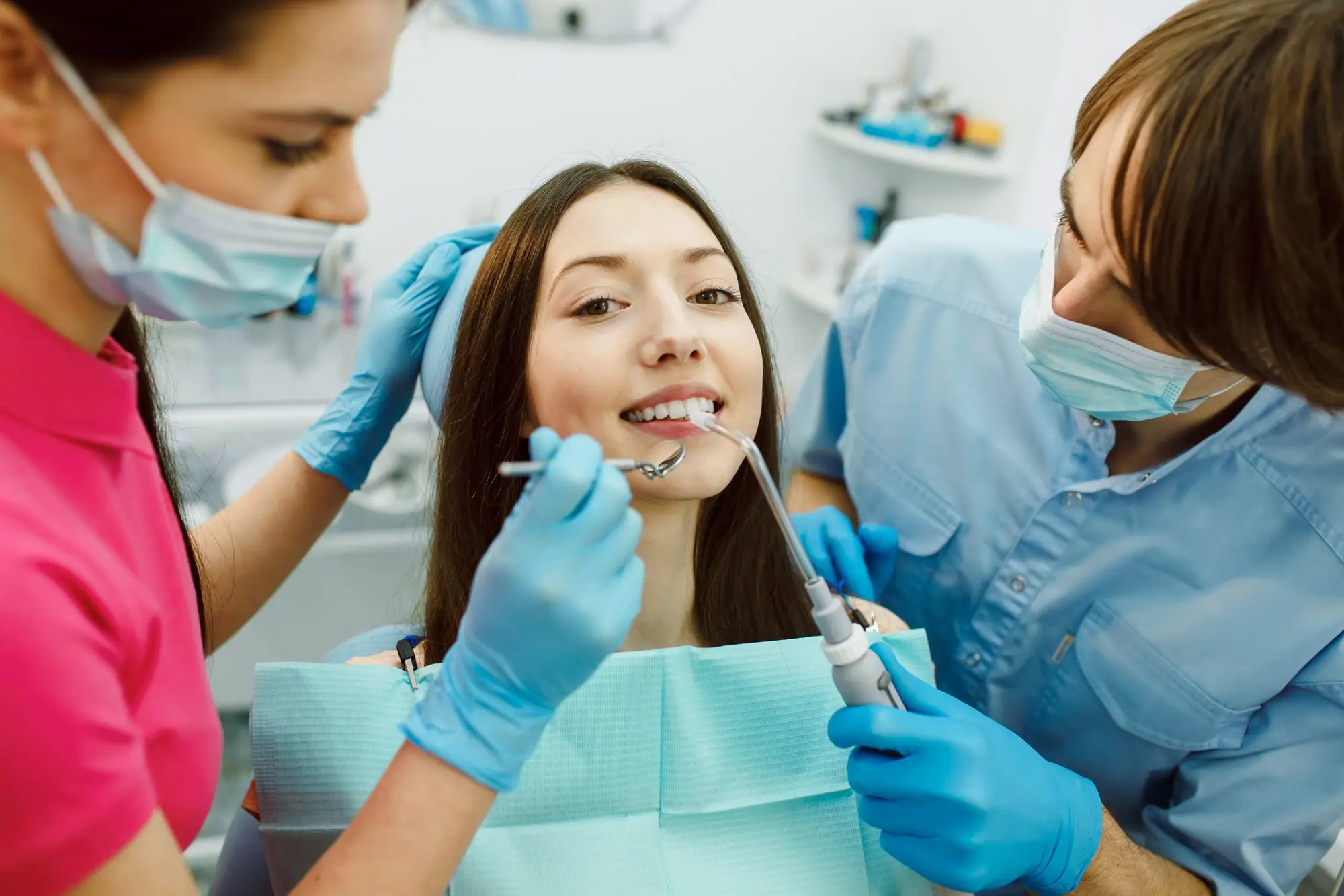 At Sweet Smiles Orthodontics in Arlington, MA, a dentist and assistant examine a woman's teeth in the dental chair with orthodontic appliances.
