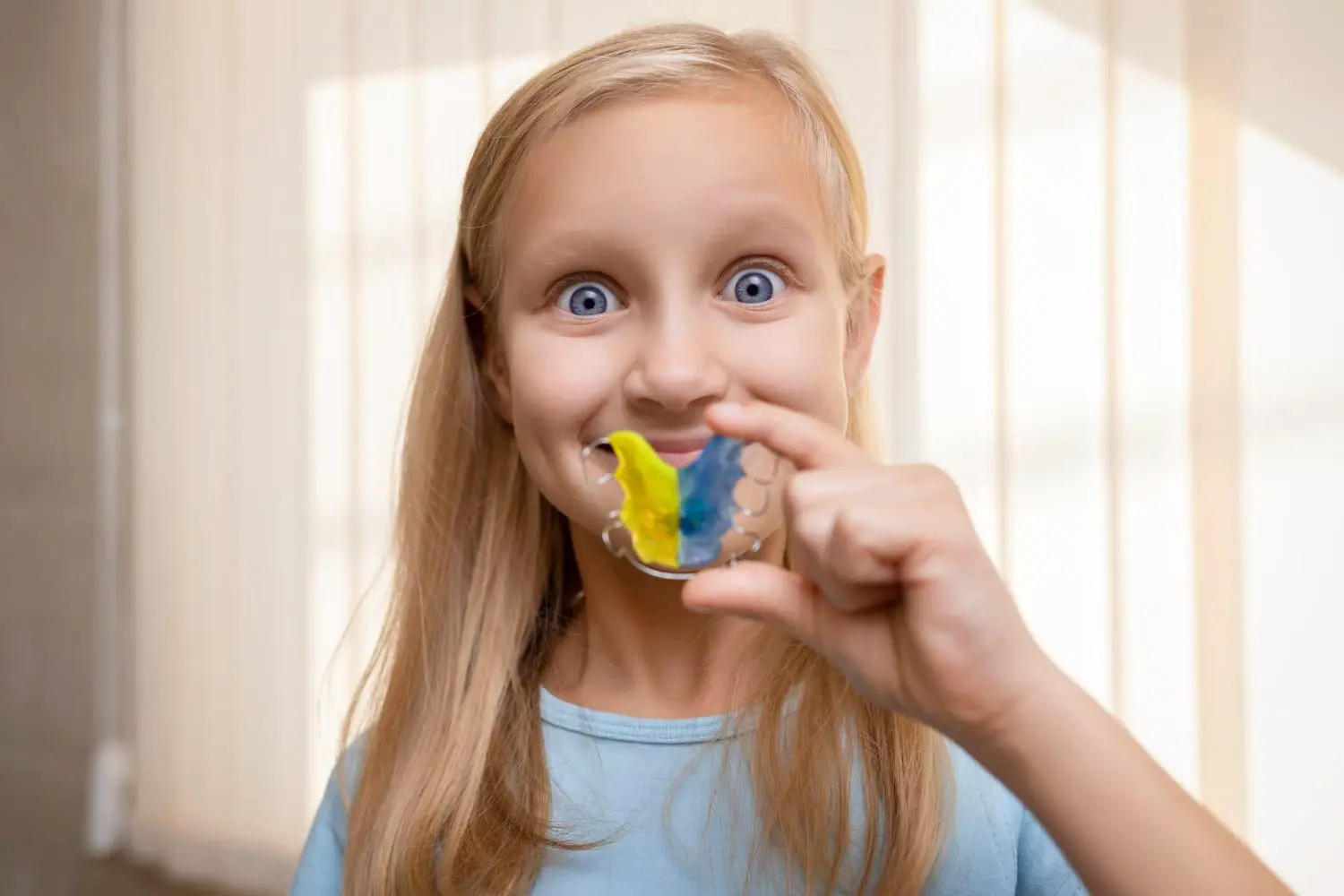 Happy young patient displaying her colorful retainers with yellow and blue elastics, showcasing
Children’s Orthodontist at Sweet Smiles Orthodontics in Arlington, MA