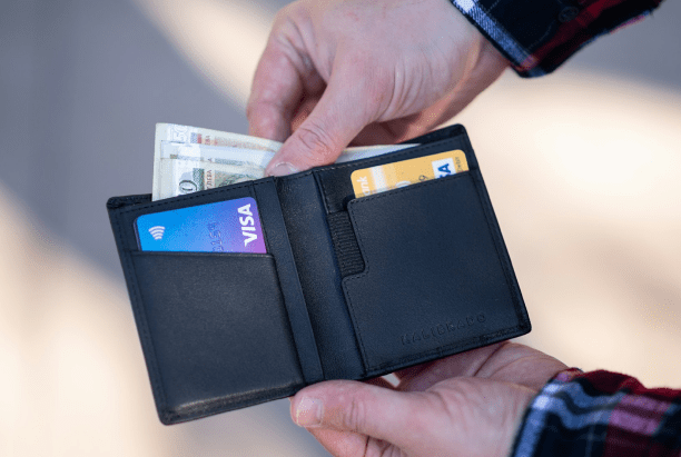 Open wallet showing cash and credit cards including Visa, representing the variety of payment methods and flexible financing options available for Invisalign treatment at Sweet Smiles Orthodontics in Arlington, MA