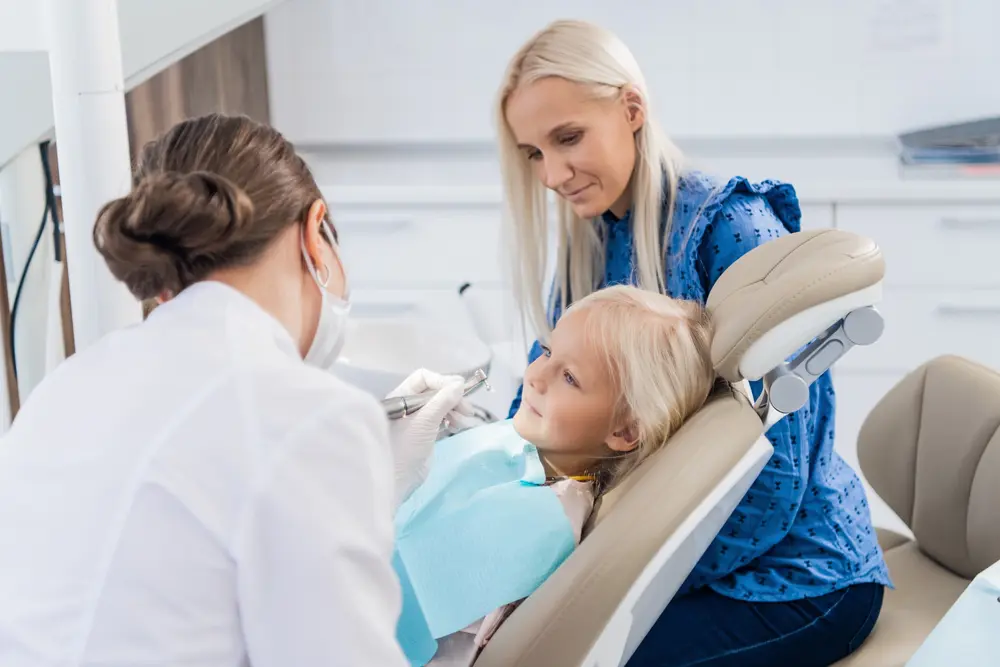 a mother watching an orthodontist taking care of her little daughters teeth - How to Fix Overbite in Arlington, MA.