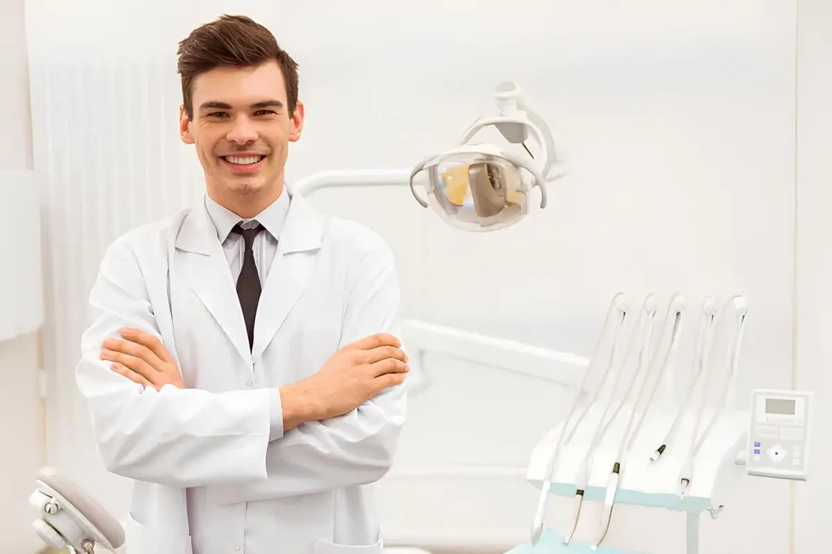 A man in a white coat stands by a dental chair at Sweet Smiles Orthodontics, Arlington MA, ready for jaw surgery