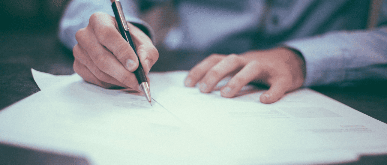 Close-up of hands signing orthodontic insurance documents with a pen on white paper, representing the enrollment and authorization process for orthodontic insurance plans at Sweet Smiles Orthodontics in Arlington, MA