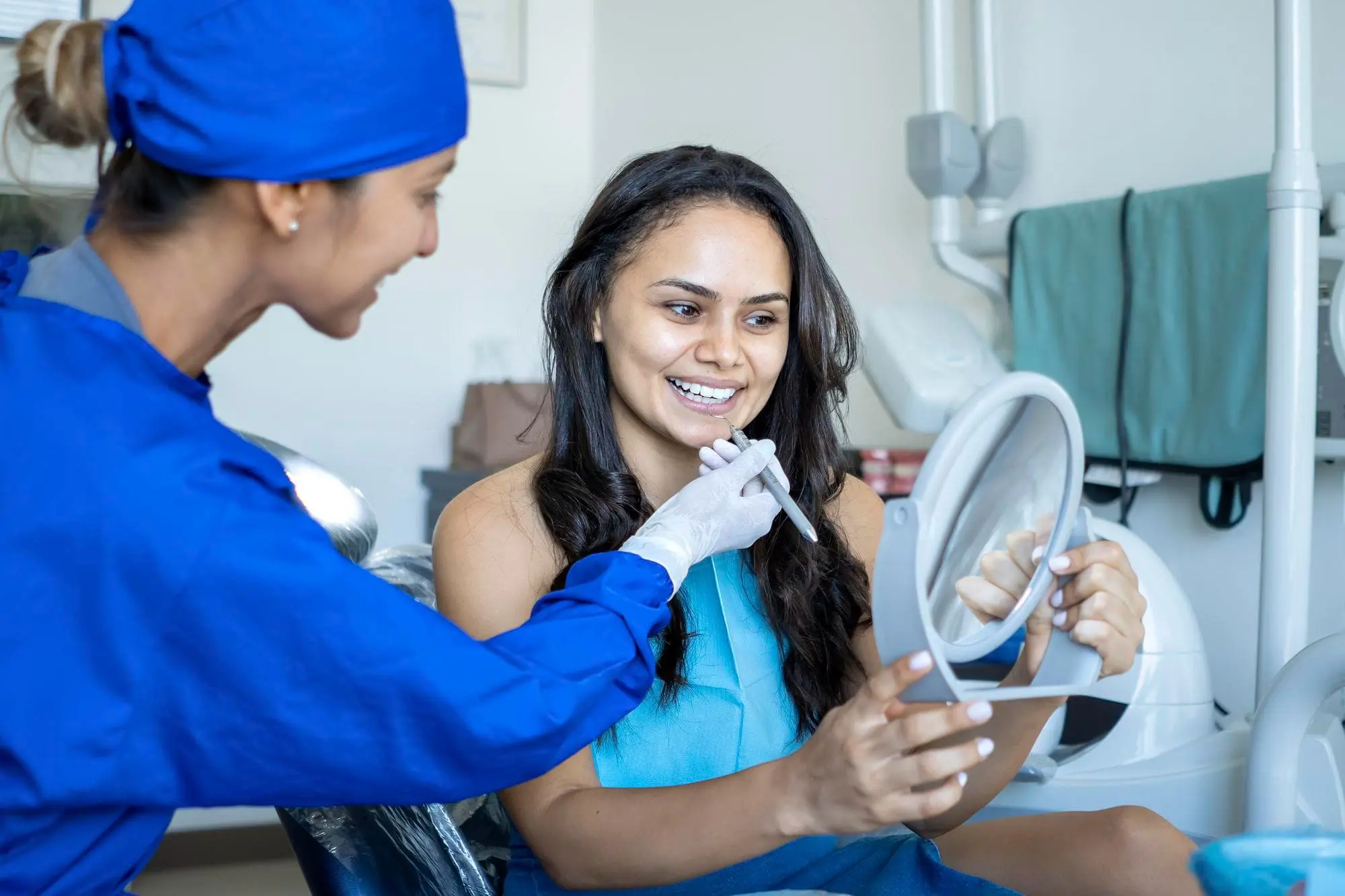 At Sweet Smiles Orthodontics in Arlington, MA, a dental professional shows a woman her teeth for the Benefits and Considerations of Adult Orthodontics.