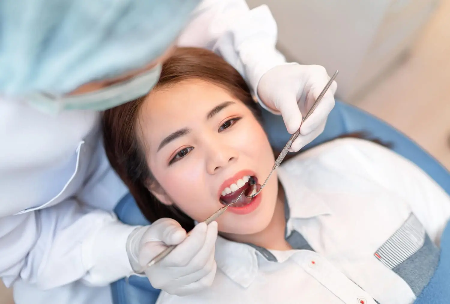 A dentist at Sweet Smiles Orthodontics in Arlington, MA, examines a woman's teeth in a dental chair, checking a palatal expander.